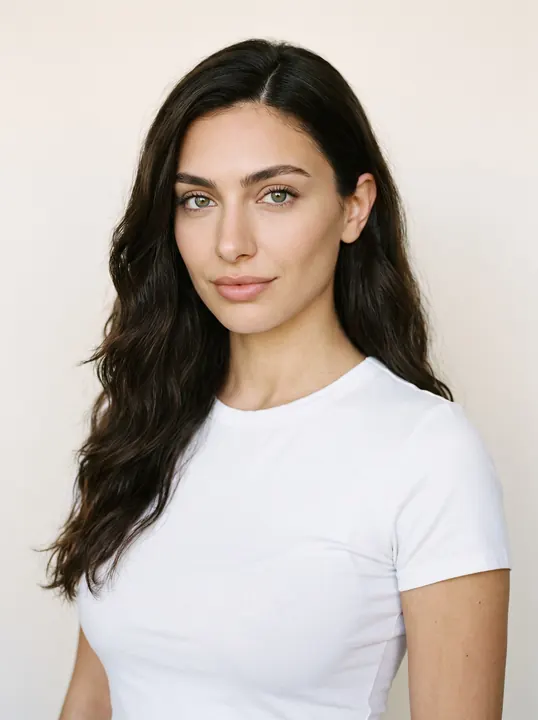 Alessia, a fictional AI model: a woman with long dark waves and green eyes, in a white tee