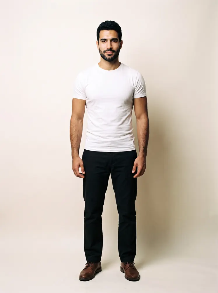 Karim, a fictional AI model: full length, with a trimmed beard, in a white tee and dark trousers