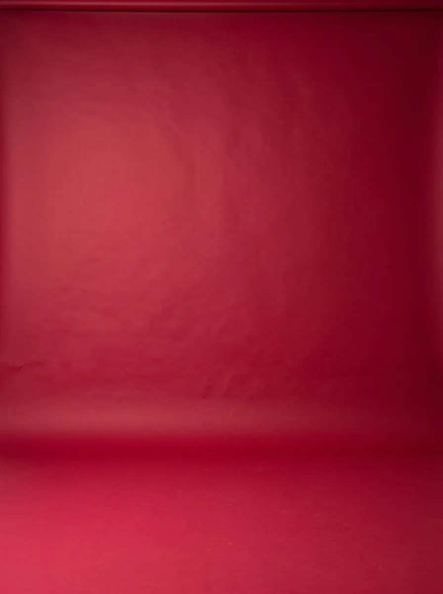 Deep crimson backdrop curving into the floor under directional light