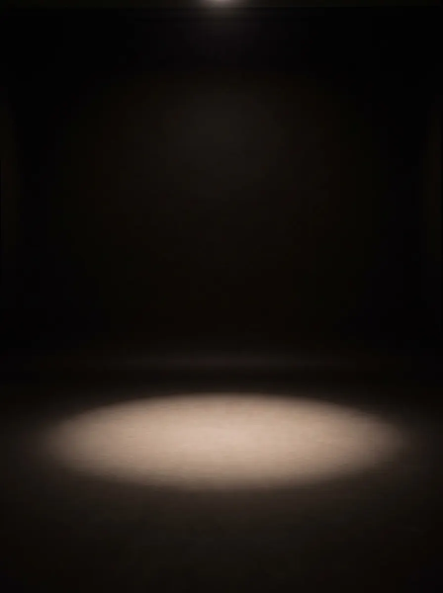 Black studio with a single soft pool of light on the floor