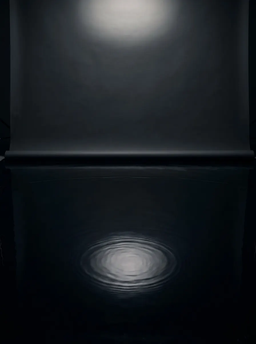 Dark set with a mirror-still water floor reflecting a soft light from above