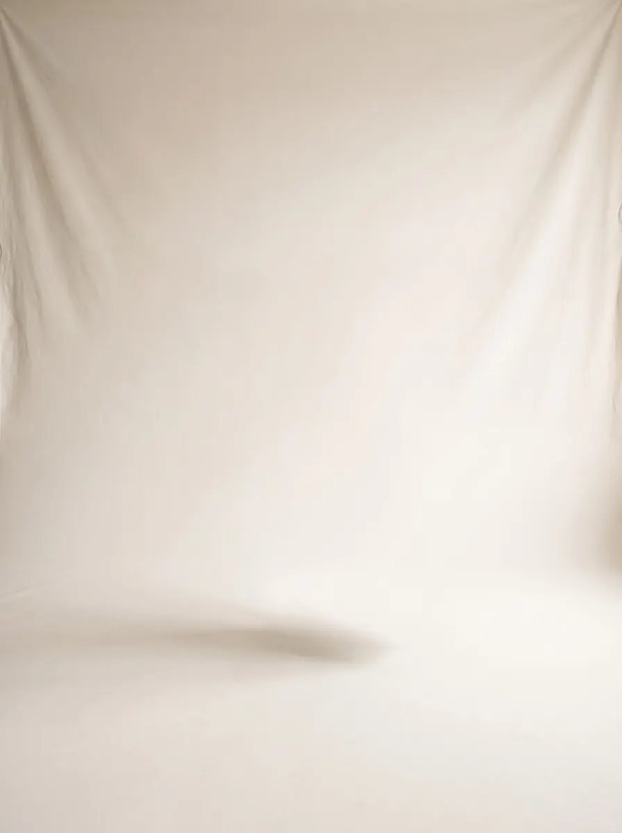 Empty studio with a warm off-white backdrop curving into the floor and a soft shadow on the floor
